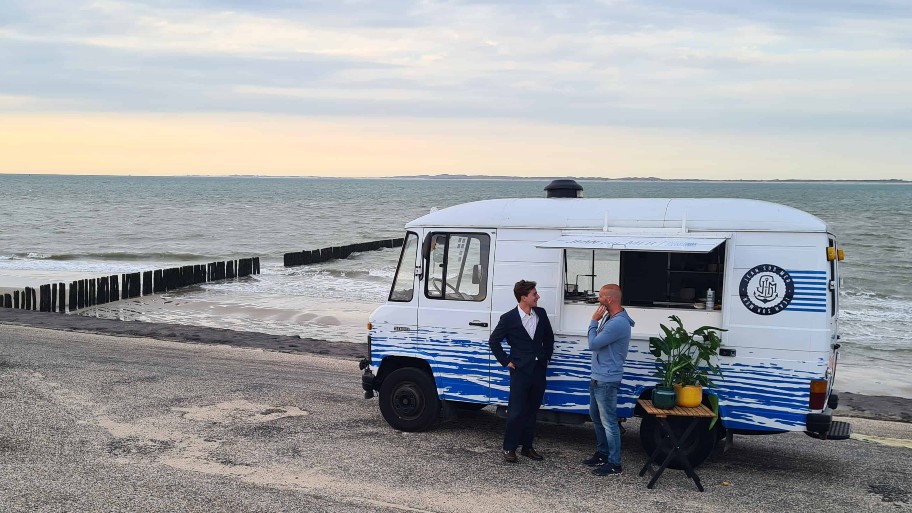 de presentator en jurylid voor een foodtruck die geparkeerd staat aan de zee