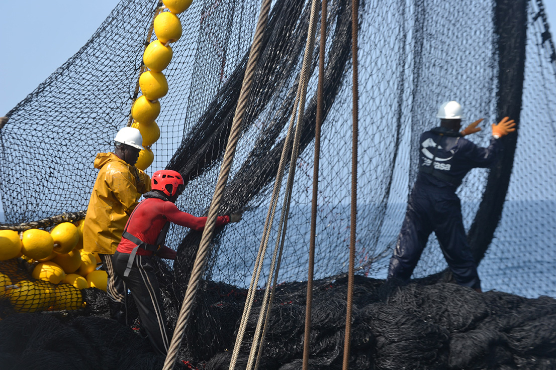 pêcheurs ramenant un filet de pêche sur le bateau