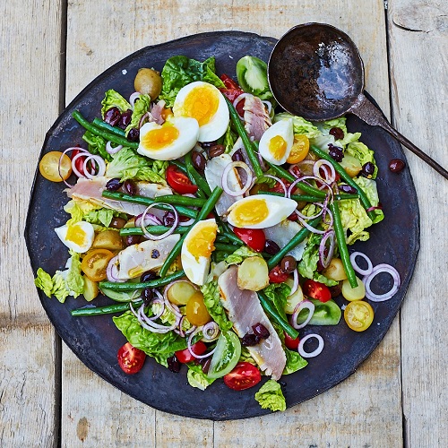 Serving suggestion for  Salade Niçoise: on a large plate with ingredients spread across the whole plate