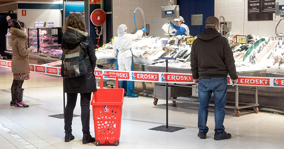 Backs of shoppers in masks at supermarket fresh fish counter