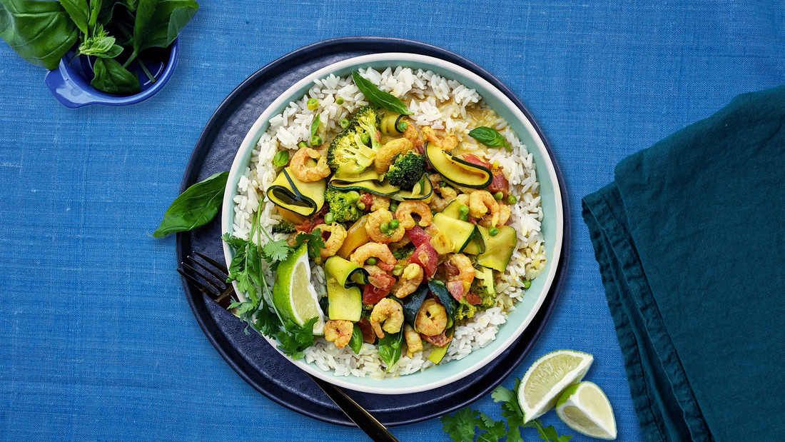 A shrimp curry dish over white rice on a blue tablecloth