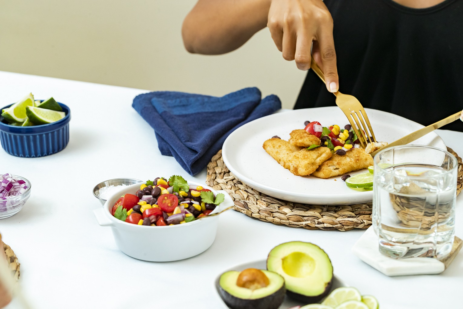 Close up of person using a fork and knife to cut lightly breaded fish