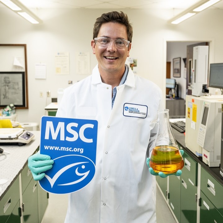 Man in lab coat holding MSC ecolabel in one hand, and flask of fish oil in the other.