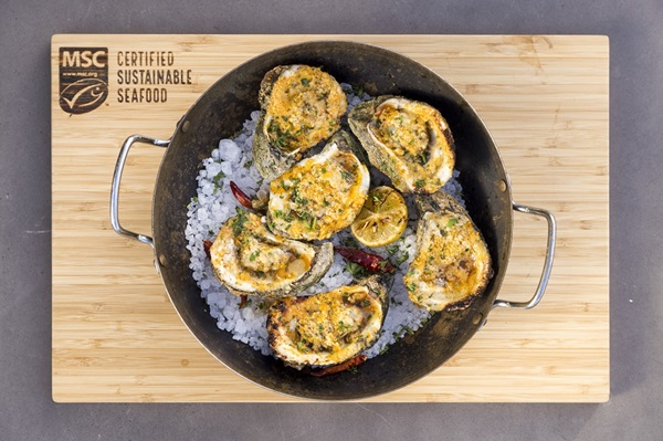 Grilled Parmesan Garlic Oysters Photo of grilled oysters topped with garlic and parmesan cheese in a pan