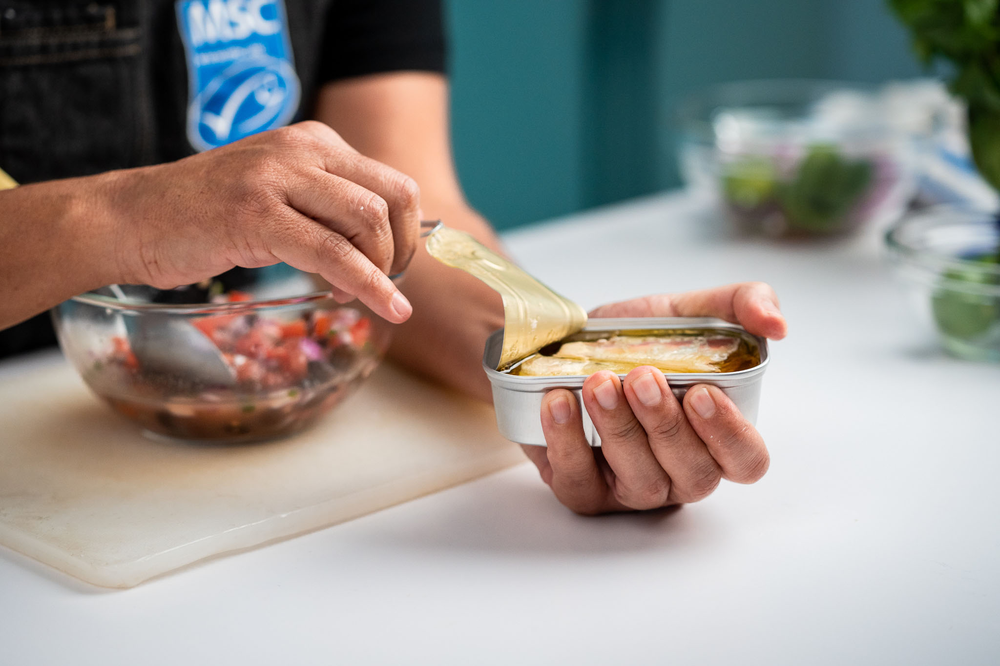 Close up image of hand opening a tin of sardines